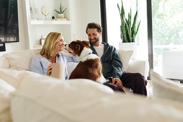 A family relaxing at home with an indoor camera on the shelf