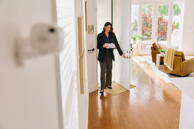 A woman arriving home as an indoor camera watches the entry